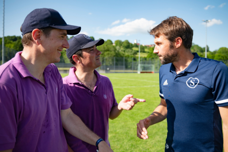 Julian Priebus auf dem Hockeyplatz im Gespräch mit zwei Altsalemern. 