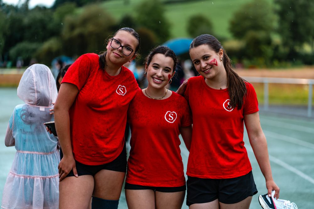 Drei Schülerinnen halten sich beim Abendsportfest in den Armen