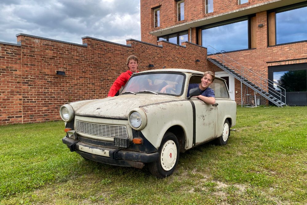 Die Brüder Braun sitzen in ihrem alten, noch unlackierten Trabbi und schauen aus dem Fenster.