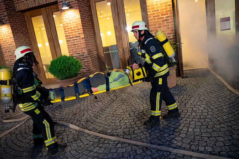 Dienstepräsentation auf dem Campus Härlen: Zwei Feuerwehrleute tragen eine Puppe aus dem brennenden Gebäude