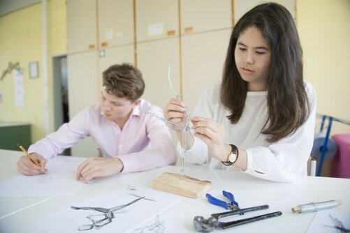 Schüler machen im Kunstunterricht eine Figur aus Draht 