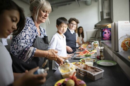 Schülerinnen und Schüler backen mit Lehrerin Waffeln in der Koch AG.