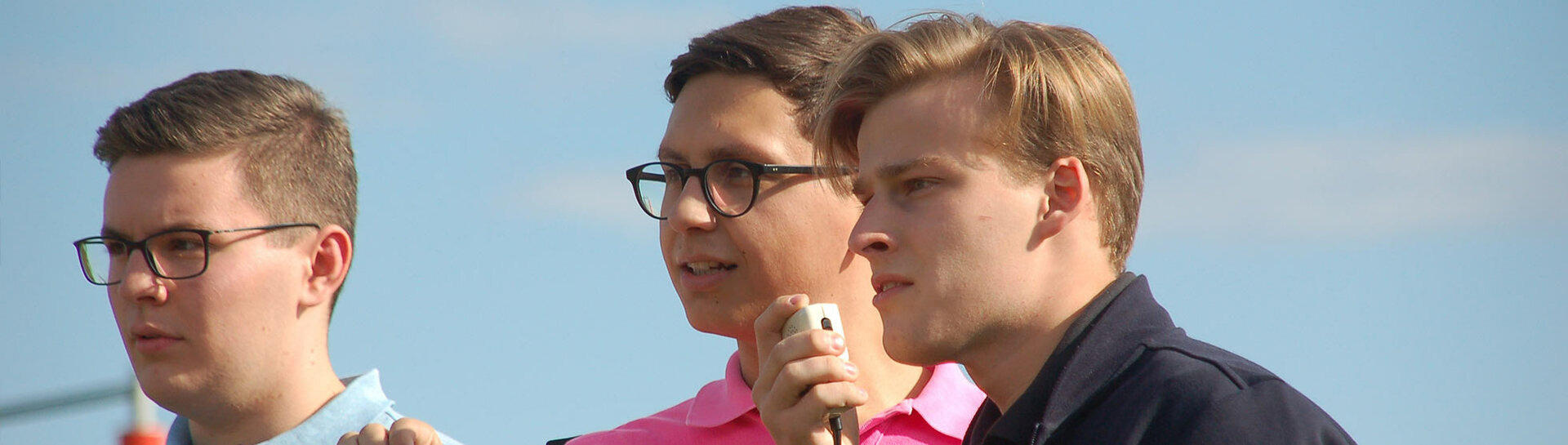 Header: Köpfe von drei Schülern, die eine Rede halten