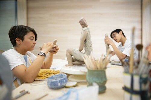 Two students work on their sculptures in the ceramic guild.