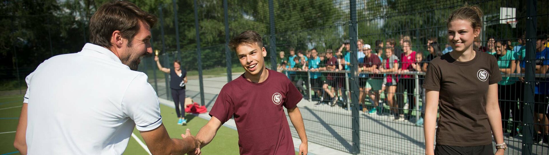 Header: Trainer gratuliert Schülern beim Abendsportfest