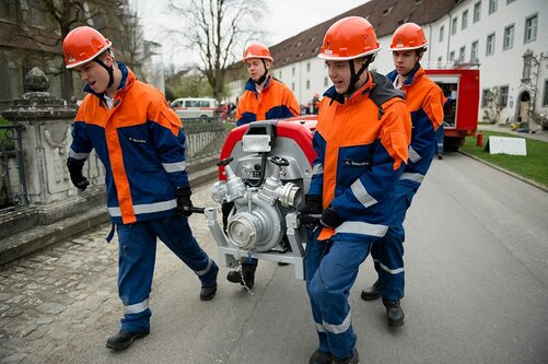 Schüler des Feuerwehrdienstes tragen Pumpe bei der Dienstepräsentation am Tag der offenen Tür