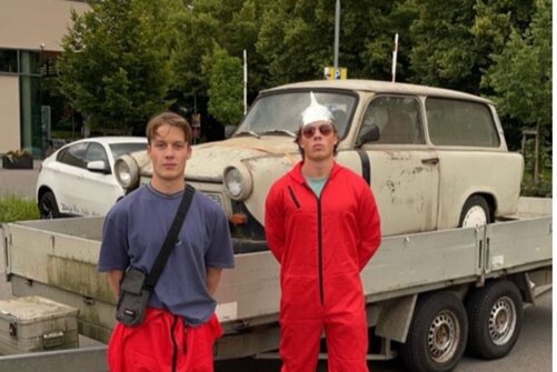 Die Brüder Braun stehen vor einem Anhänger, auf dem ein alter Trabbi steht.