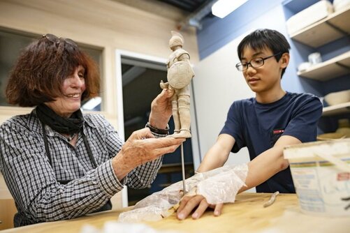 A pupil is working on a sculpture with the support of the guild director.