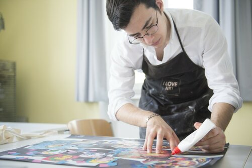 Kunst: Schüler klebt ein Plakat im Kunstunterricht 